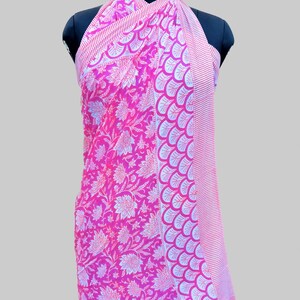 Op de afbeelding: Roze en witte katoenen sarong met een bloemenprint en een rand van witte en roze schelpen. De sarong is over een mannequin gedrapeerd.