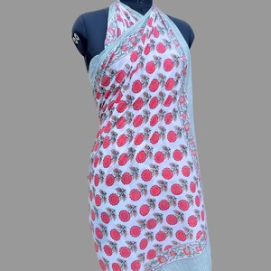 Op de afbeelding: Witte katoenen sarong met een rode bloemenprint. De sarong is om een ​​mannequin gebonden om te laten zien hoe hij als jurk gedragen kan worden.