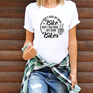 May include: White t-shirt with a black graphic that says "I don't ride my own bike, but I do ride my own biker".