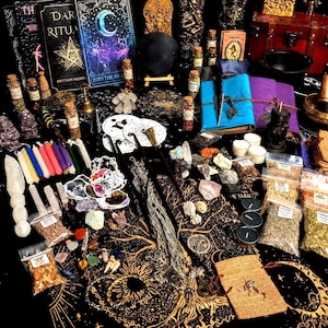 May include: A collection of occult supplies including books titled Dark Rituals and Into the Night, various glass vials with herbs, colorful taper candles, crystals, metal charms, a black cauldron, a wooden chest, and a black cloth with gold tree print.
