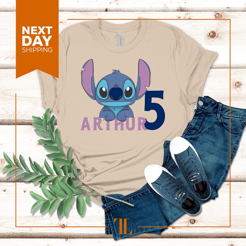 May include: Tan t-shirt with a blue Stitch character from Lilo & Stitch, the number 5, and the name Arthur in purple lettering.