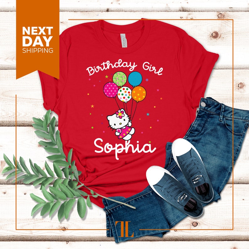 Puede incluir: Camiseta roja con un dise&ntilde;o blanco de Hello Kitty sosteniendo globos que dicen "Birthday Girl" y el nombre "Sophia" impreso debajo.