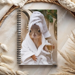 May include: A squirrel wearing a white bathrobe and a white towel on its head, sitting in a chair and holding a glass of champagne.