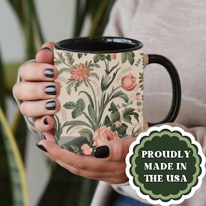 May include: A black ceramic mug with a floral pattern and the text "Forch Thriving" repeated throughout. The mug is being held by a person's hand. The text "Proudly Made in the USA" is visible in a green circle.