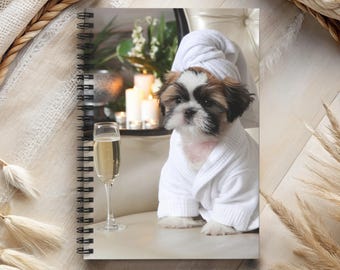 May include: A small, white dog wearing a white bathrobe and a white towel on its head. The dog is sitting on a white chair with a glass of champagne in front of it.