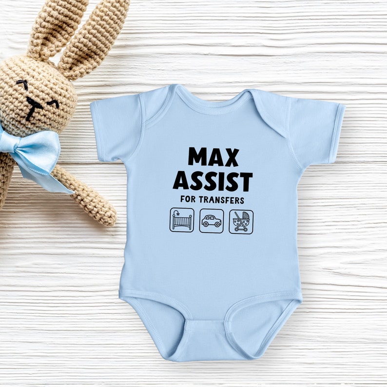 Może przedstawiać: Jasno niebieski śpioszek dla niemowlęcia z napisem "Max Assist for Transfers" i ikonami ł&oacute;żeczka, samochodu i w&oacute;zka.