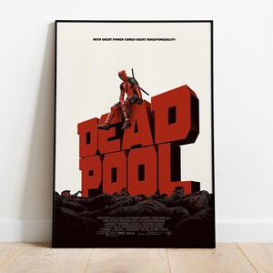 Puede incluir: Un p&oacute;ster enmarcado con la palabra "DEADPOOL" en letras grandes, rojas y en 3D. El superh&eacute;roe Deadpool est&aacute; sentado sobre las letras. El p&oacute;ster tiene el texto "WITH GREAT POWER COMES GREAT IRRESPONSIBILITY" en la parte superior.