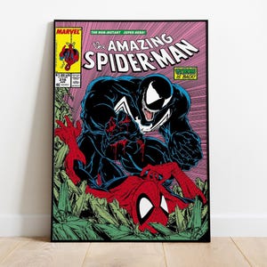 May include: A comic book cover print of The Amazing Spider-Man issue 316 featuring Venom looming over Spider-Man. The artwork displays a black Venom character with a white spider emblem and a red and blue Spider-Man figure amidst green debris.