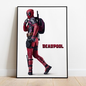 Puede incluir: P&oacute;ster enmarcado del personaje Deadpool con un traje rojo y negro, con una mochila negra. La palabra "DEADPOOL" est&aacute; impresa en rojo. El personaje est&aacute; en una pose con un dedo en los labios.