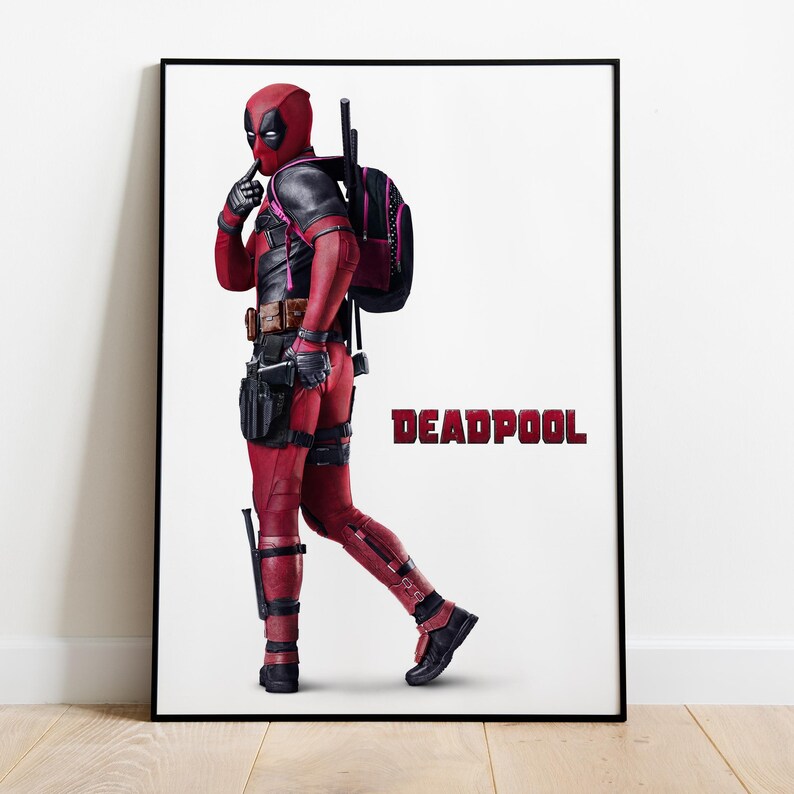 Puede incluir: P&oacute;ster enmarcado del personaje Deadpool con un traje rojo y negro, con una mochila negra. La palabra "DEADPOOL" est&aacute; impresa en rojo. El personaje est&aacute; en una pose con un dedo en los labios.