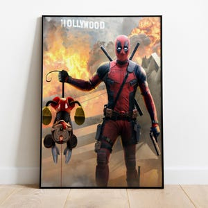 Puede incluir: P&oacute;ster enmarcado que muestra a Deadpool con un traje rojo y negro, sosteniendo un personaje de dibujos animados boca abajo. El fondo muestra una explosi&oacute;n de fuego y la palabra "HOLLYWOOD". Deadpool est&aacute; armado con espadas y una pistola.