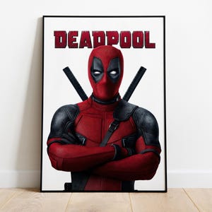 Puede incluir: P&oacute;ster enmarcado de Deadpool. La imagen muestra a Deadpool con su traje rojo y negro, con los brazos cruzados y dos katanas en la espalda. La palabra "DEADPOOL" est&aacute; impresa en letras rojas en la parte superior.