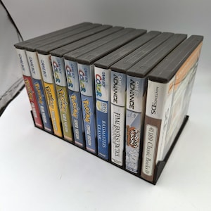 May include: A collection of video game cartridges for the Game Boy Color and Game Boy Advance consoles. The cartridges include titles such as Pokemon, Bass Masters Classic, Final Fantasy Tactics, and Harvest Moon.