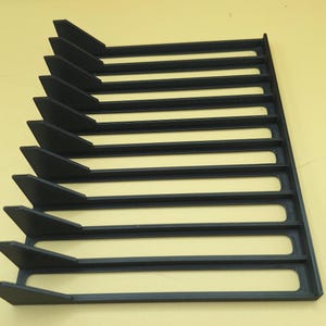Right side view of a black video game or DVD storage tray in 10 slots featuring wall extensions at the front of each slot to better secure the cases and a slightly elevated back wall. Each slot has a large hole in the base.