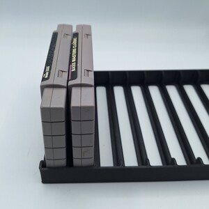 May include: Two gray Super Nintendo game cartridges in a black plastic game cartridge holder. The game cartridges are labeled "Bass Masters Classic".