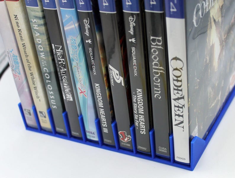 Front view of a blue video game or DVD storage tray in 10 slots featuring wall extensions at the front of each slot to better secure the cases. Ten video games are displayed in the tray.