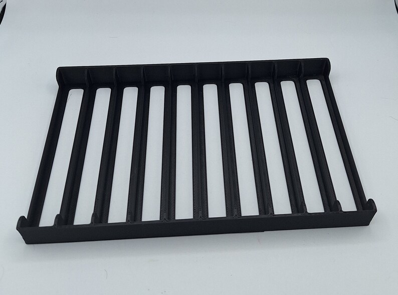 May include: Black plastic storage rack with 10 compartments. The rack is empty.