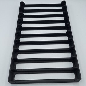 May include: Black plastic organizer with eight slots, designed to hold and display small items.
