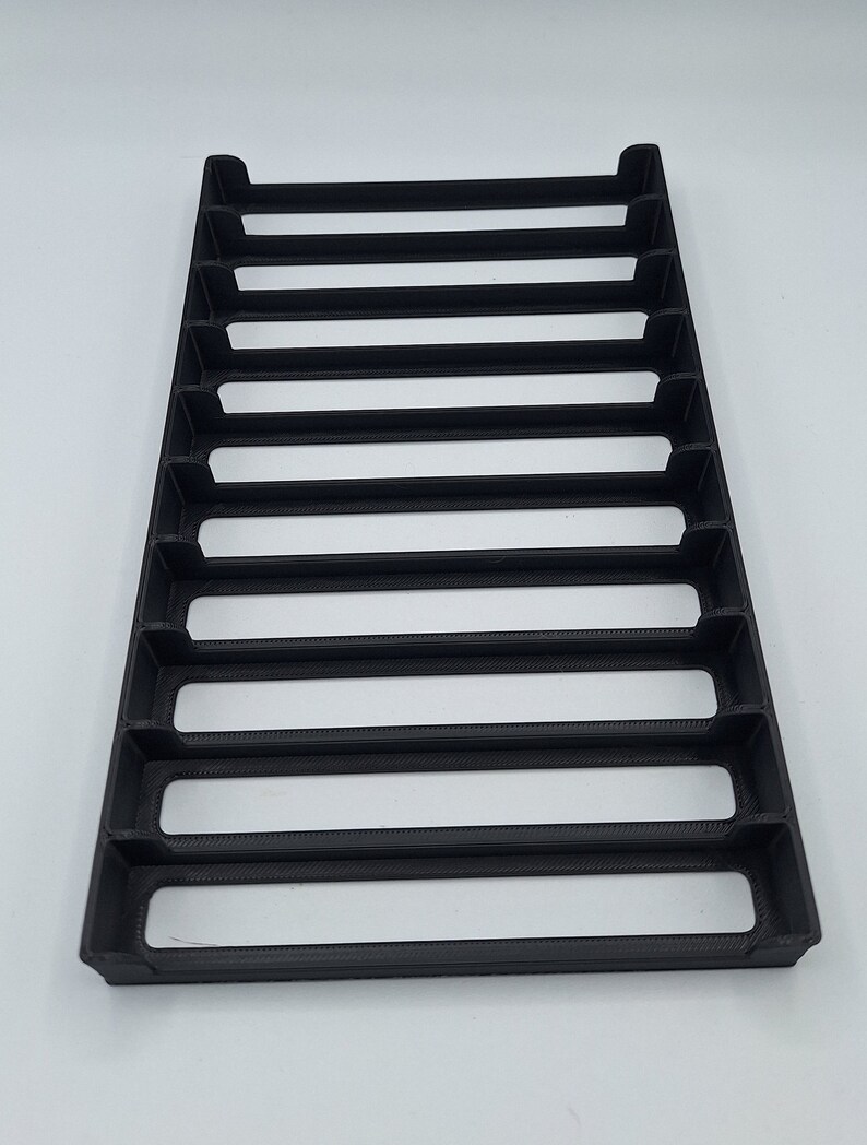 May include: Black plastic organizer with eight slots, designed to hold and display small items.