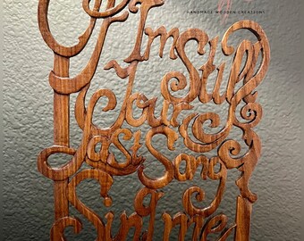 May include: Wooden sign featuring the text "If I'm Still Your Last Song, Sing Me" in a decorative font. The sign is crafted from rosewood and has a natural wood finish. It is a handmade wooden creation.