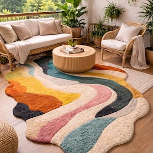 May include: A vibrant, abstract rug featuring a flowing design in yellow, orange, pink, blue, and cream. The rug sits on a wooden floor, complementing the wicker furniture and plants, creating a relaxed outdoor living area. The rug's dimensions are approximately 200cm x 300cm.