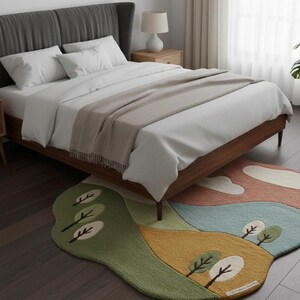 May include: A bedroom scene featuring a bed with white linens, a gray headboard, and a wooden frame. A colorful, landscape-themed rug with trees and hills is on the floor. A bedside table with a lamp is visible.