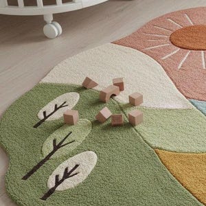 May include: A colorful, whimsical rug with a landscape design featuring a sun, trees, and hills in shades of green, pink, and yellow. Wooden blocks are scattered across the rug. A white crib is in the background.