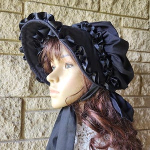 May include: A white ceramic mug with a black handle and the text "But First, Coffee" in a bold, black font. The mug is set against a blurred background, suggesting a cozy setting.