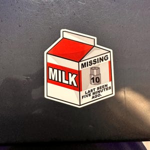 May include: A sticker featuring a carton of milk with the word "MILK" in bold letters. The carton has a red top and the text "MISSING" above an image of a missing item. The text "LAST SEEN FIVE MINUTES AGO" is below.