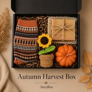 Fall gift box for women featuring a cozy autumn gift basket beautifully arranged in a premium black gift box with pumpkin accent, warm knit socks, sunflower detail, botanical candle, artisan soap and harvest-inspired gifts. Harvest Bliss Box is styled in rich orange, brown, golden yellow and cream fall colors, perfect as a Thanksgiving gift, hostess gift, fall birthday gift, pumpkin care package, autumn gift basket or cozy gift for her.