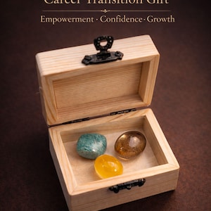 May include: A wooden box with a black clasp, open to reveal three polished gemstones: a teal, a yellow, and a brown stone. The text "Career Transition Gift" and "Empowerment, Confidence, Growth" are at the top.