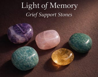 May include: Five polished stones in shades of purple, pink, green, and yellow are arranged on a brown surface. The text "Light of Memory Grief Support Stones" is displayed above the stones.