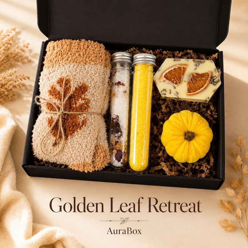 Fall gift box for women featuring a cozy autumn gift basket beautifully arranged in a premium black gift box with pumpkin accent, warm knit socks, sunflower detail, botanical candle, artisan soap and harvest-inspired gifts. Harvest Bliss Box is styled in rich orange, brown, golden yellow and cream fall colors, perfect as a Thanksgiving gift, hostess gift, fall birthday gift, pumpkin care package, autumn gift basket or cozy gift for her.