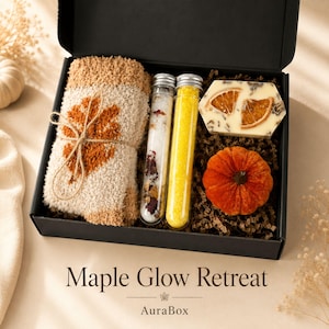 Fall gift box for women featuring a cozy autumn gift basket beautifully arranged in a premium black gift box with pumpkin accent, warm knit socks, sunflower detail, botanical candle, artisan soap and harvest-inspired gifts. Harvest Bliss Box is styled in rich orange, brown, golden yellow and cream fall colors, perfect as a Thanksgiving gift, hostess gift, fall birthday gift, pumpkin care package, autumn gift basket or cozy gift for her.