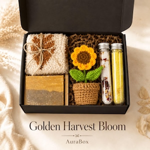Fall gift box for women featuring a cozy autumn gift basket beautifully arranged in a premium black gift box with pumpkin accent, warm knit socks, sunflower detail, botanical candle, artisan soap and harvest-inspired gifts. Harvest Bliss Box is styled in rich orange, brown, golden yellow and cream fall colors, perfect as a Thanksgiving gift, hostess gift, fall birthday gift, pumpkin care package, autumn gift basket or cozy gift for her.