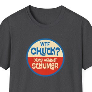 May include: Dark gray t-shirt with a circular graphic. The graphic features the text "WTF CHUCK?" in blue and white, with "DEMS AGAINST SCHUMER" in red. The design is centered on the chest.