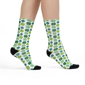 Puede incluir: Calcetines blancos con un estampado repetido de tréboles verdes en varios tonos. Los calcetines tienen talones y punteras negras. Estos calcetines son ideales para el Día de San Patricio y miden unos 30 cm de largo.