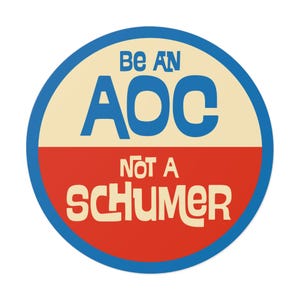 May include: A round sticker with a blue border and a white and red center. The text on the sticker reads "Be an AOC not a Schumer" in a retro font.