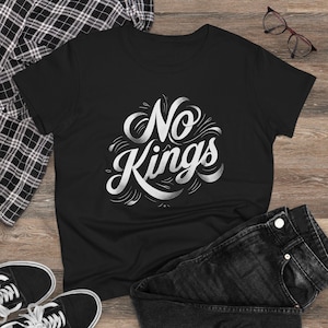 以下が含まれることがあります： スタイリッシュなフォントで「No Kings」という白文字がプリントされた黒いTシャツ。黒いジーンズ、白と黒のスニーカー、チェックのシャツと組み合わせています。メガネも写っています。
