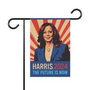 May include: A red, white, and blue garden flag with a portrait of Kamala Harris. The flag reads "Harris 2024 The Future Is Now".