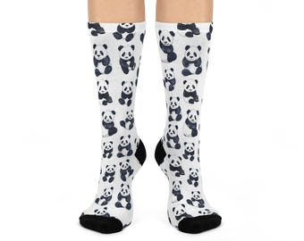 Op de afbeelding: Witte sokken met een herhaald patroon van zwart-witte panda-beren illustraties. De sokken hebben zwarte hielen en tenen, en de panda's staan in verschillende poses.