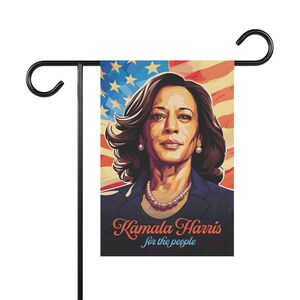 May include: A garden flag featuring a portrait of Kamala Harris against a red, white, and blue American flag background. The text "Kamala Harris for the people" is printed below the portrait.