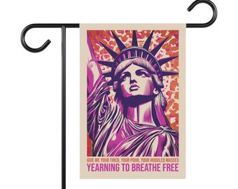 Könnte beinhalten: Eine Gartenflagge mit einer Vintage-Illustration der Freiheitsstatue in Rosa- und Lilatönen. Die Flagge hat einen beigefarbenen Hintergrund mit einem rosa-orangenen Tarnmuster. Der Text auf der Flagge lautet "Give me your tired, your poor, your huddled masses yearning to breathe free."
