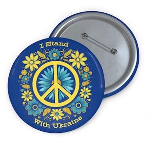 Könnte beinhalten: Ein blauer und gelber Knopf mit einem Friedenszeichen, das von Blumen umgeben ist. Der Text "I Stand With Ukraine" steht auf dem Knopf.
