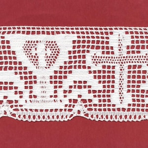 May include: Close-up of a white, crocheted lace trim with a repeating geometric pattern. The lace features a scalloped edge and a design incorporating crosses and other shapes. The background is a solid red color.