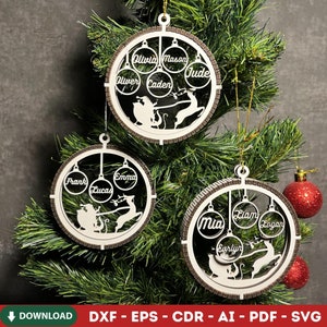 Könnte beinhalten: Drei personalisierte Weihnachtskugeln mit Namen wie Olivia, Mason und Jude werden auf einem Weihnachtsbaum präsentiert. Jede Kugel hat ein kreisförmiges Design mit einer Silhouette von Santa und Rentieren. Die Ornamente sind aus hellem Holz mit einem dunkelbraunen Rand gefertigt.