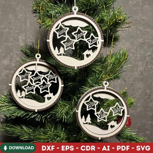 May include: Three wooden Christmas ornaments hanging on a green tree. Each ornament is a circle with a star-shaped cutout containing names. The ornaments have a light brown border and a white interior with a house and tree design.
