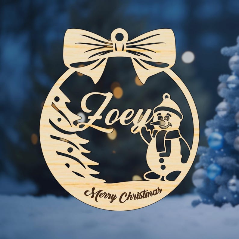 K&ouml;nnte beinhalten: Ein h&ouml;lzerner Weihnachtsbaumschmuck in Form einer Kugel mit einem Schneemann und einem Weihnachtsbaum. Der Anh&auml;nger ist mit dem Namen "Joey" und dem Text "Frohe Weihnachten" personalisiert.