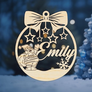 K&ouml;nnte beinhalten: Ein h&ouml;lzerner Weihnachtsbaumschmuck in Form einer Kugel mit einer Schleife oben. Der Schmuck zeigt eine Weihnachtsmannfigur, Sterne, eine Schneeflocke und den Namen "Emily".