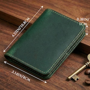 May include: A dark green leather wallet with visible stitching. The wallet measures 4.25 inches by 3.14 inches and is 0.39 inches thick. A vintage key and coffee beans are in the background.